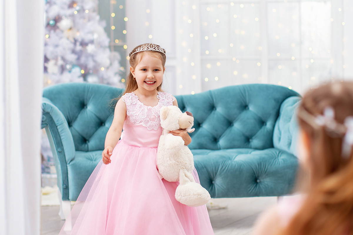 una bambina vestita da principessa che si guarda allo specchio