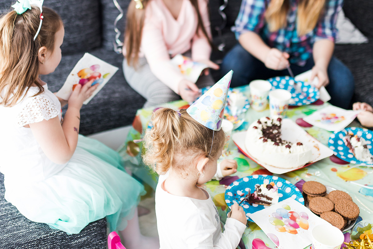 bambini intorno ad un tavolo con dolci e giochi di compleanno