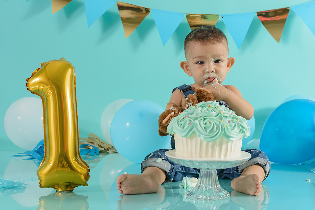 Bambino che mangia la torta del suo primo compleanno