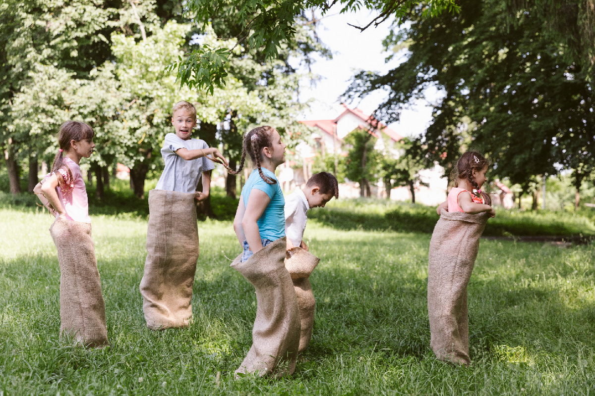 Bambini che giocano saltando dentro dei sacchi di patate
