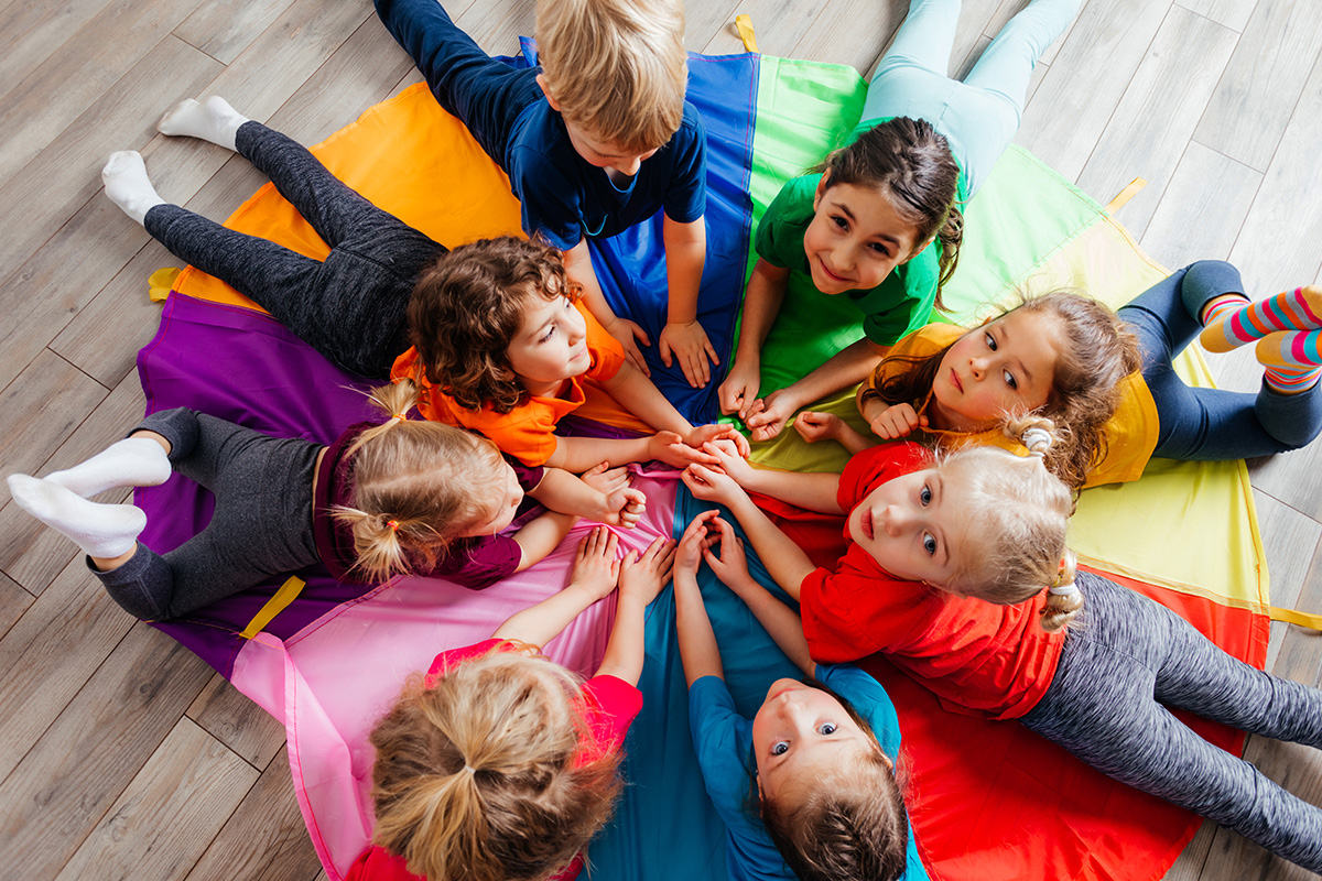 bambini sdraiati in cerchio sopra un telo colorato