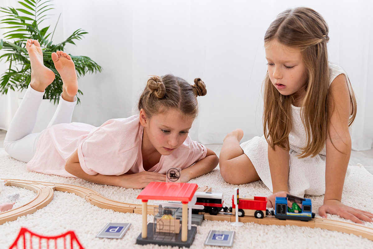 due bambine che giocano con una pista di macchinine giocattolo